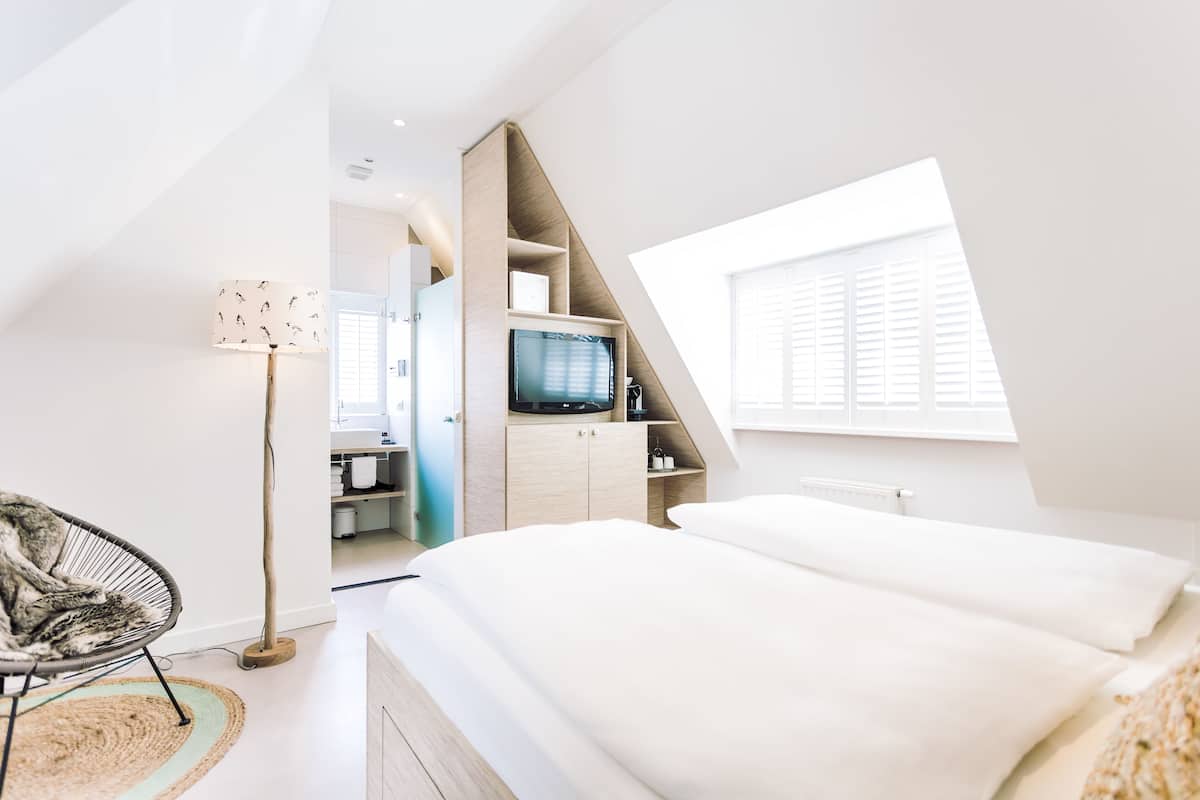 A modern bedroom with a bed, a TV, and a wardrobe.