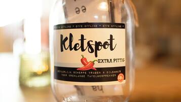 Un barattolo etichettato 'Kletspot' con un'illustrazione di peperoncino, su un piano di legno.