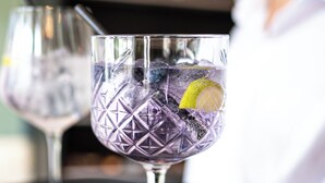 Two glasses of a clear beverage with ice and a slice of lime, placed on a black tray. - Logement Overzee (Nes)