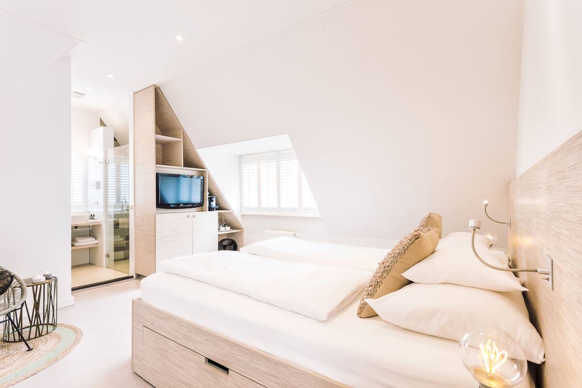A bedroom with a bed, a TV, a wardrobe, and a desk.