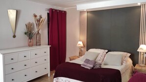 A bedroom with a bed, nightstands, a dresser, a mirror, and a curtain.