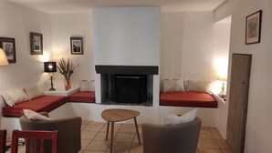 A cozy living room with a fireplace, seating areas, and a small table.