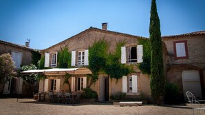 A rustic building with ivy-covered walls, a thatched roof, and a courtyard with outdoor seating.