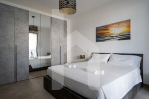 Une chambre moderne avec un grand lit, une armoire et un tableau représentant un coucher de soleil.