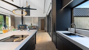 A modern kitchen with a central island, a built-in stove, and a large window. - Countryside Escape Arrowtown (Arrowtown)