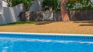 Ein Swimmingpool mit Holzzaun und Baum im Hintergrund.