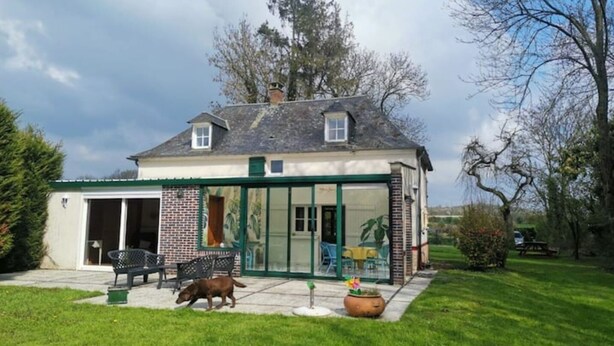 A house with a covered patio, a dog, and a lawn.
