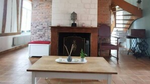 A spacious room with a fireplace, a dining table, and a hanging light fixture.