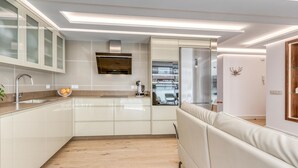 Une cuisine moderne avec des meubles blancs, un four encastré et un réfrigérateur en acier inoxydable.