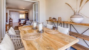 A dining area with a wooden table, woven placemats, and a large vase on a shelf. - Sun-Drenched Apartment in Estepona - 2BR, Pools, Near Beaches & Old Town (Estepona)