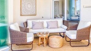A cozy living area with wicker furniture, a white sofa, and a woven coffee table. - Sun-Drenched Apartment in Estepona - 2BR, Pools, Near Beaches & Old Town (Estepona)