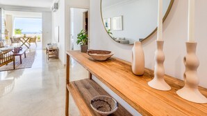A modern living room with a wooden console table, a large mirror, and two white candle holders. - Sun-Drenched Apartment in Estepona - 2BR, Pools, Near Beaches & Old Town (Estepona)