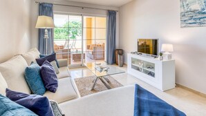 Una sala de estar moderna con un sofá, televisor y una mesa de centro de vidrio.