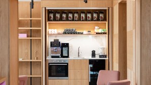 Una cocina moderna con armarios de madera, un comedor con mesa y sillas, y una cafetera integrada.