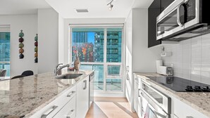 Una cocina moderna con encimeras de granito, electrodomésticos de acero inoxidable y un amplio ventanal con vistas a la ciudad.