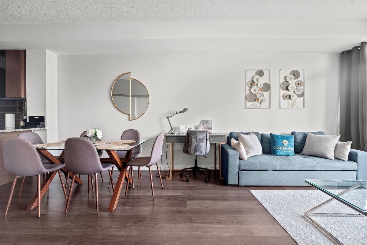 Ein modernes Wohnzimmer mit Essbereich, einer Couch und einem Glastisch.