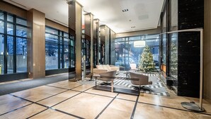Un vestíbulo moderno con un gran árbol de Navidad, asientos cómodos y amplias ventanas con vistas a la ciudad.