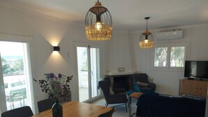 A living room with a dining table, chairs, a sofa, and two hanging lights. - 5 bedroom villa in l'escala (L'Escala)