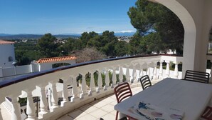 A balcony with a white railing, a table, and chairs. - 5 bedroom villa in l'escala (L'Escala)