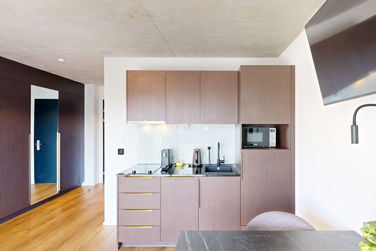 A compact kitchen with wooden cabinets, a microwave, and a sink.
