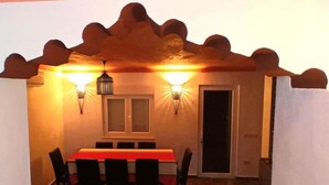 Un espace repas comprenant une table et des chaises, deux lampes fixées au mur et une porte.