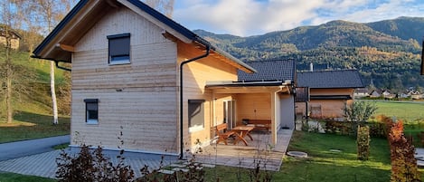 A modern wooden house with a covered patio and a mountain view.