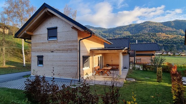 Une maison moderne en bois dotée d’un patio couvert et offrant une vue sur la montagne.