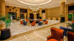 A spacious lobby with a modern chandelier, comfortable seating areas, and a large plant. - Taj Gandhinagar Resort & Spa (Mansa)