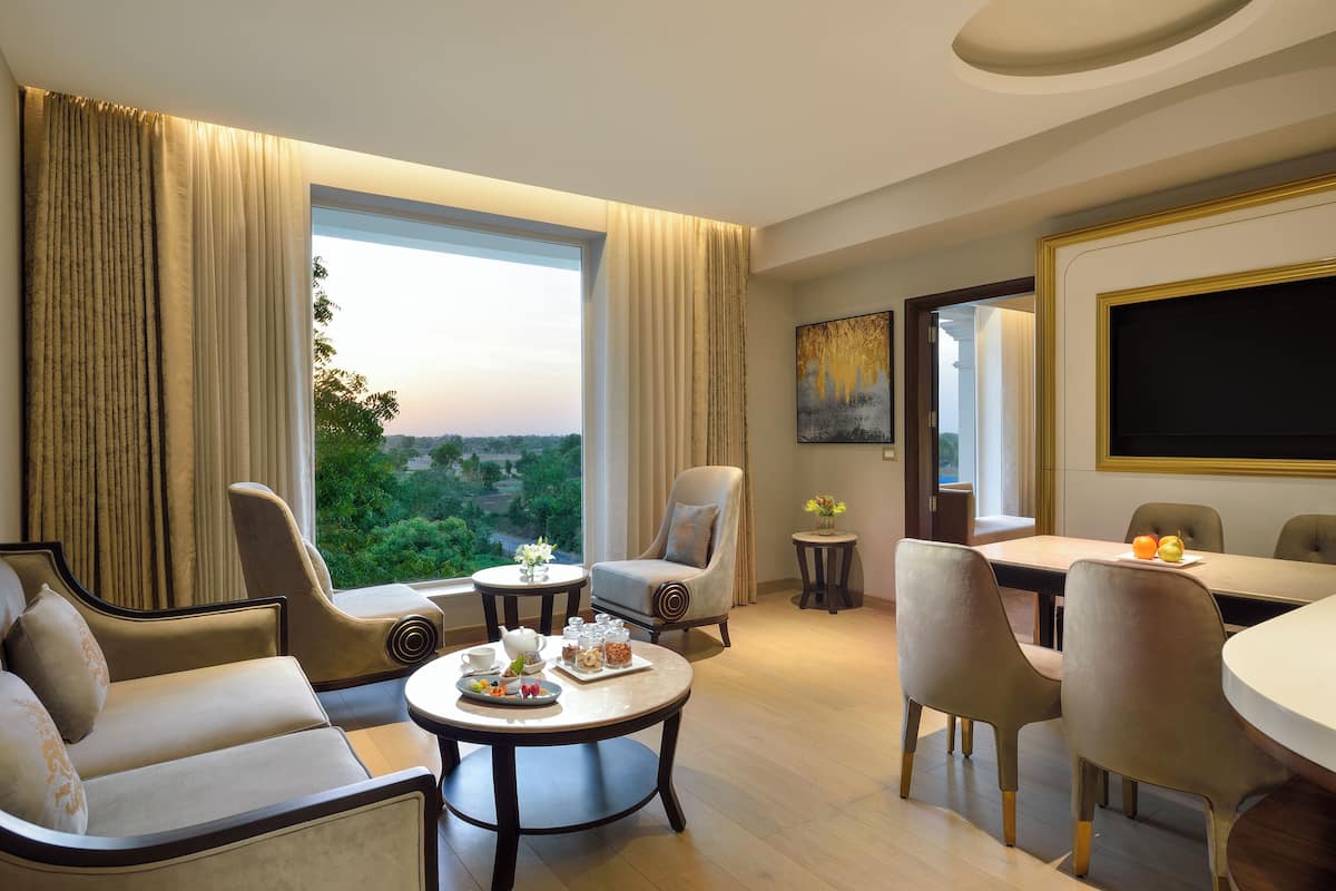 A hotel room with a large window, a dining area, and a seating arrangement.