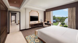 A hotel room with a large bed, a desk with a computer, a TV, and a view of the outdoors. - Taj Gandhinagar Resort & Spa (Mansa)
