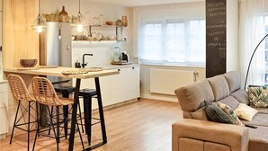 A modern kitchen with a central island, two bar stools, a sofa, and a chalkboard with a welcome message. - Stunning apartment in Vimianzo with WiFi (Vimianzo)