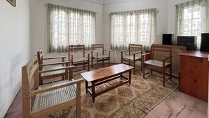 Una habitación con muebles de madera, incluyendo sillas y una mesa, y un televisor sobre un mueble de madera.