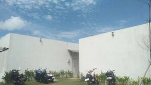 Un patio con paredes blancas, una entrada pequeña y varias motocicletas estacionadas.