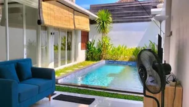 Una sala moderna con un sofá azul, una piscina y un ventilador.