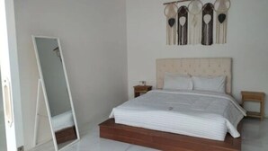 Un dormitorio con cama, espejo y lámpara de pared.