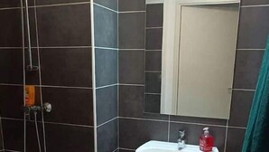 Een badkamer met een douche, een wastafel en een spiegel.