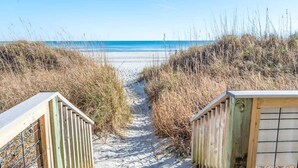 A sandy beach path leading to the ocean, flanked by wooden structures and tall grasses. - New Corner Direct Oceanfront View - 5th Floor - Pools (North Myrtle Beach)