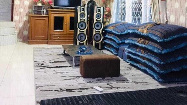 Ein Wohnzimmer mit Fernseher, Lautsprechern, einer Couch und einer Wand mit Muster.