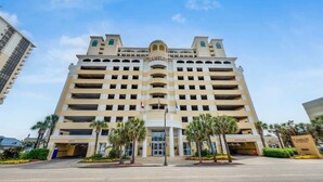 Un hotel de varios pisos con entrada central, varios balcones y un letrero llamativo.
