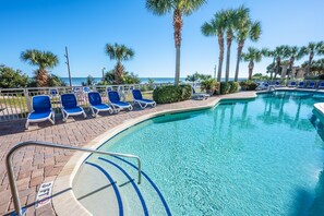 Relax by the serene pool surrounded by palm trees and lounge chairs.