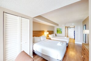 Two single beds with white linens and wooden headboard, a dresser and mirror, and a large window with blinds.