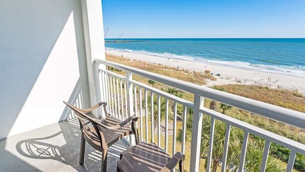 A balcony with two chairs overlooking a beach. - Direct Oceanfront Amazing Views In Camelot Resort! (Myrtle Beach)