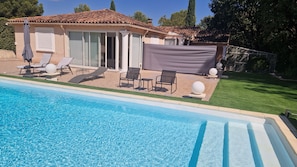 Une piscine avec des chaises longues et un espace patio couvert.