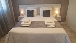 Une chambre d’hôtel avec un grand lit, deux lampes de chevet, une table de chevet et un porte-serviettes.