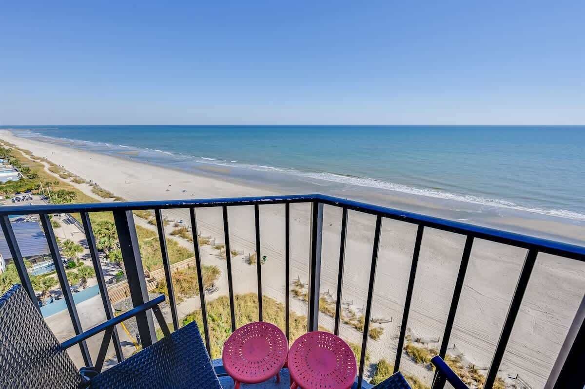 A balcony with a view of a beach and ocean.