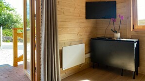 Un intérieur en bois avec un téléviseur fixé au mur, un radiateur et une petite table sur laquelle est posée une plante en pot.