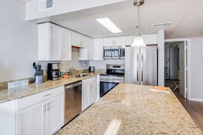A modern kitchen with white cabinets, stainless steel appliances, and a granite countertop.