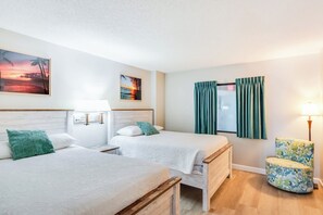 A hotel room with two beds, a nightstand with a lamp, a chair, and a window with curtains. - Sand Dunes Resort 7th Floor Direct Oceanfront Pool (Myrtle Beach)