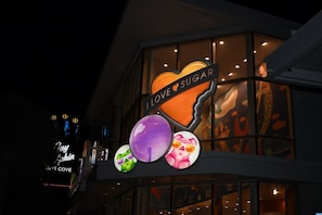 A building with a heart-shaped sign that reads "I LOVE SUGAR" and a neon sign for "Day Skin" in the background. - Sand Dunes Resort 7th Floor Direct Oceanfront Pool (Myrtle Beach)