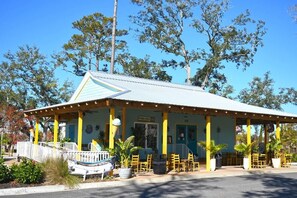 A building with a covered patio area, yellow pillars, and outdoor seating. - Sand Dunes Resort 7th Floor Direct Oceanfront Pool (Myrtle Beach)